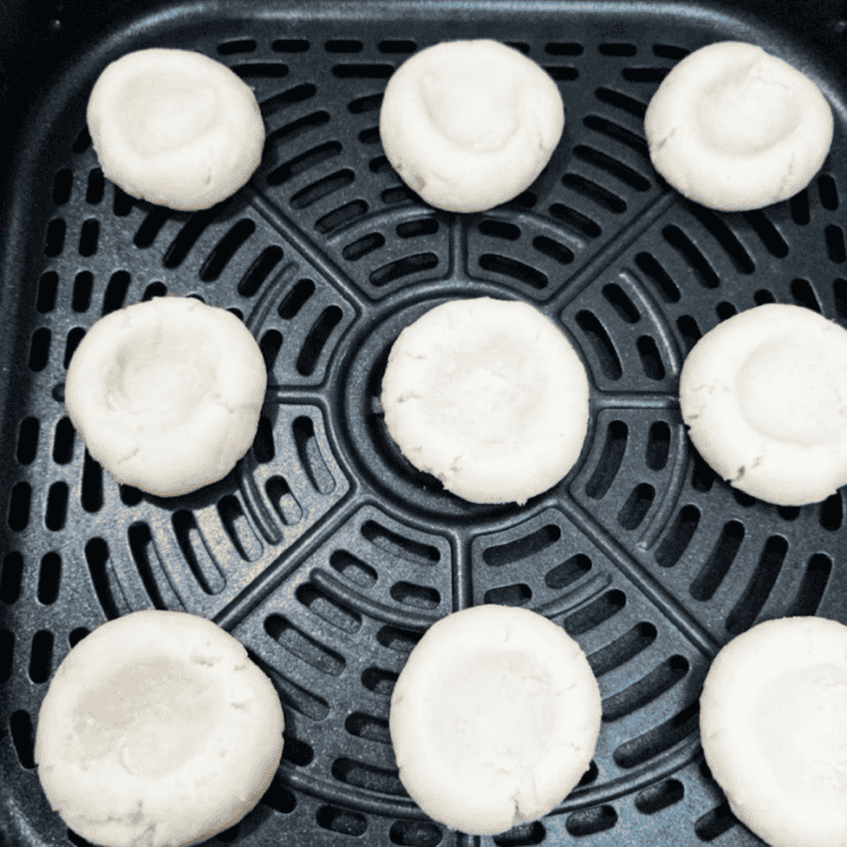 Rolling cookie dough into small balls on a parchment-lined air fryer tray.