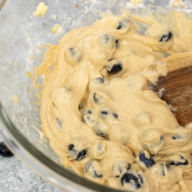 Stirring egg, milk, and oil into the dry ingredients to form blueberry bread batter