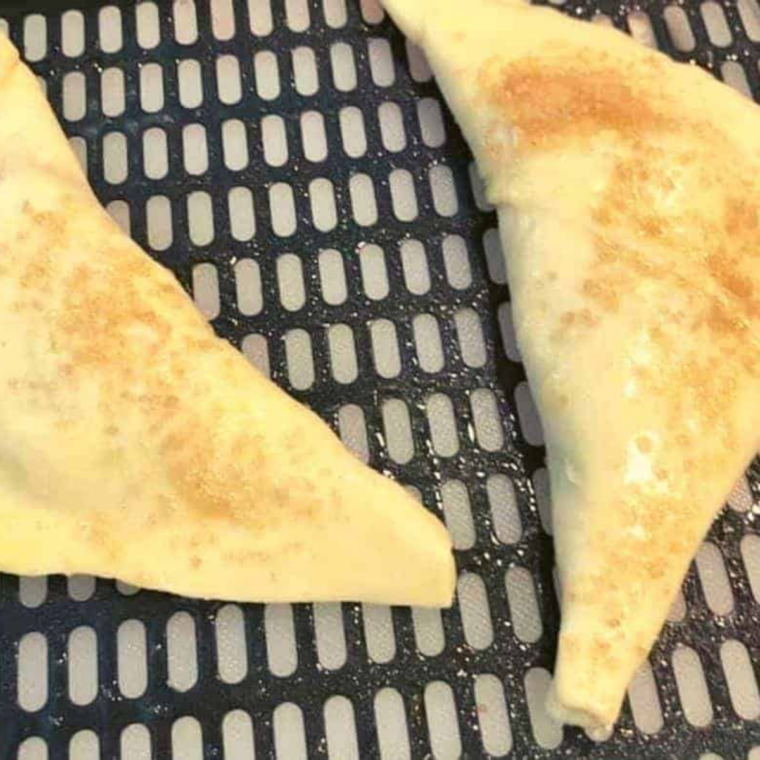 Egg wash being brushed on top of puff pastry blueberry turnovers for shine.
