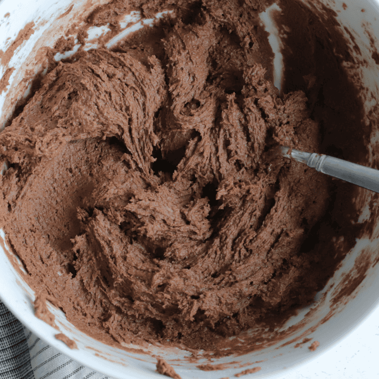 Cookie dough being mixed with chocolate chunks and caramel bites.