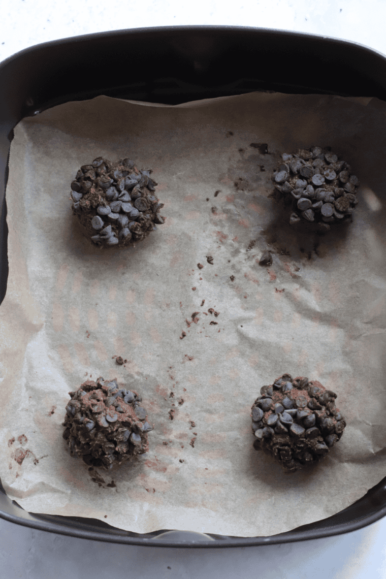 Air fryer basket with flattened cookie dough balls ready to bake.