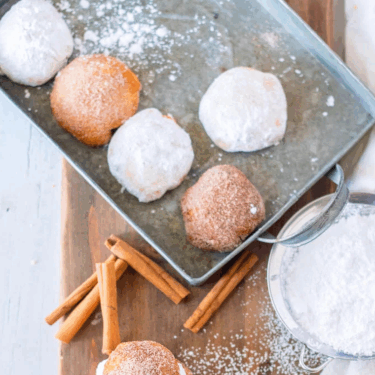Golden air fryer donut holes generously dusted with powdered sugar on a plate.