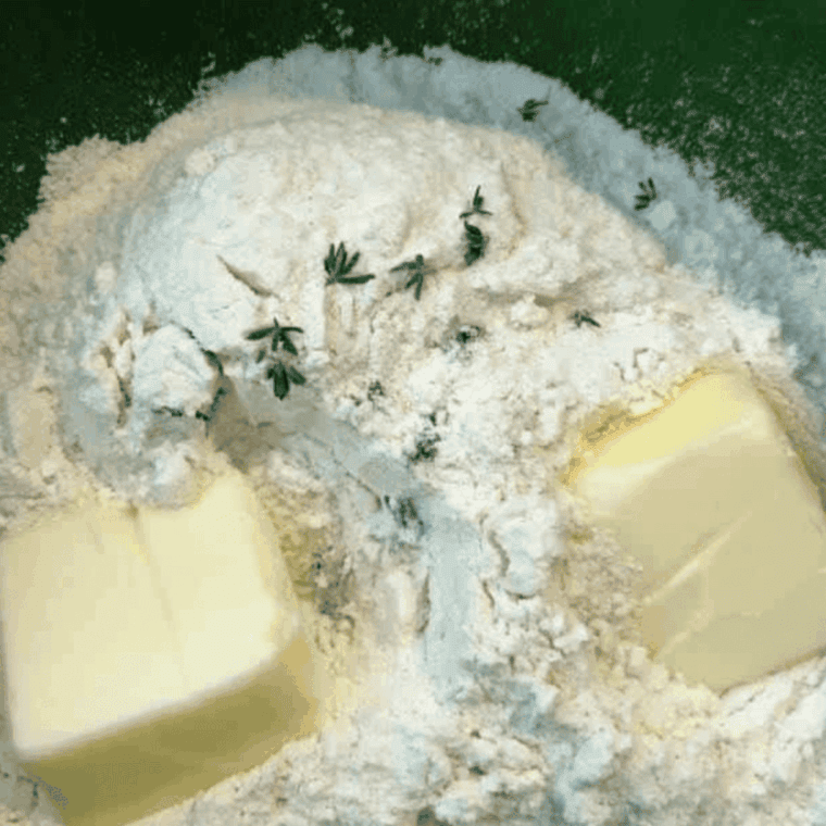 Mixing flour, baking powder, sugar, salt, cream, butter, cheddar, and thyme in a bowl.
