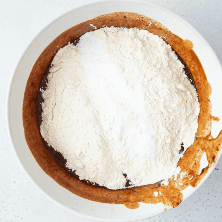 Mixing dry ingredients in bowl followed by wet ingredients for smooth chocolate cake batter consistency