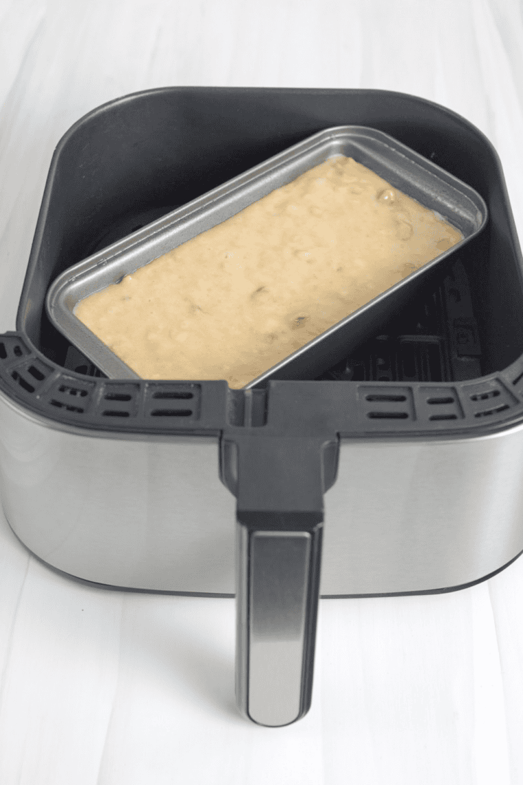 Batter in greased air fryer loaf pan cooking at 320 degrees Fahrenheit.