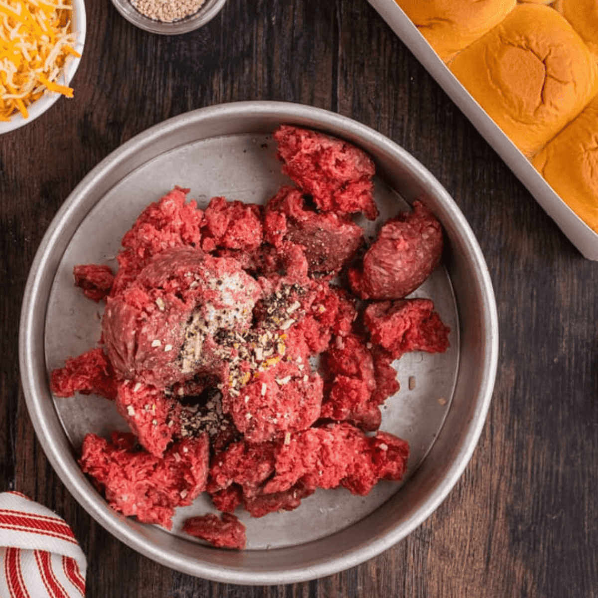 Ground beef in an air fryer pan mixed with taco seasoning, olive oil, and lime juice, ready to cook at 400°F for 5–7 minutes.