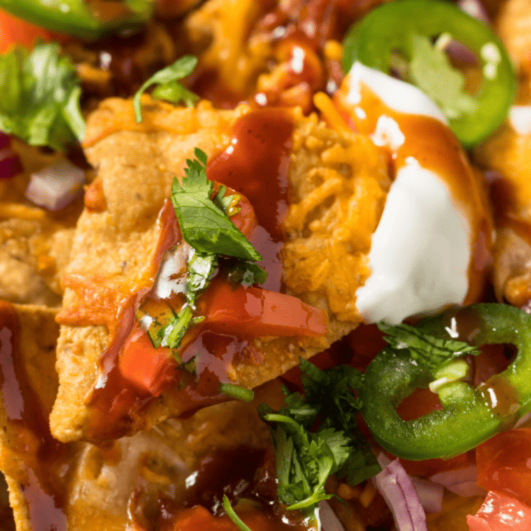 Loaded BBQ pork nachos with melted cheese, smoky pulled pork, BBQ sauce, jalape&ntilde;os, sour cream, and fresh toppings served over crispy tortilla chips for sharing.