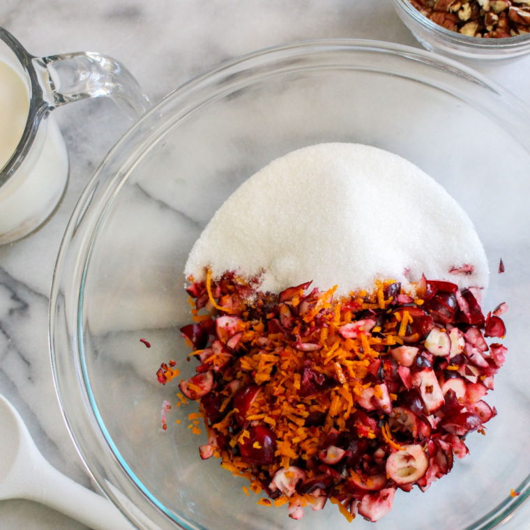 Chopped fresh cranberries and walnuts being folded into cranberry orange bread batter with a spatula