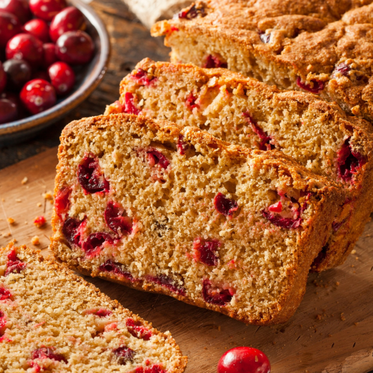 Sliced air fryer cranberry orange nut bread showing a tender crumb with tart cranberries and chopped walnuts in every slice