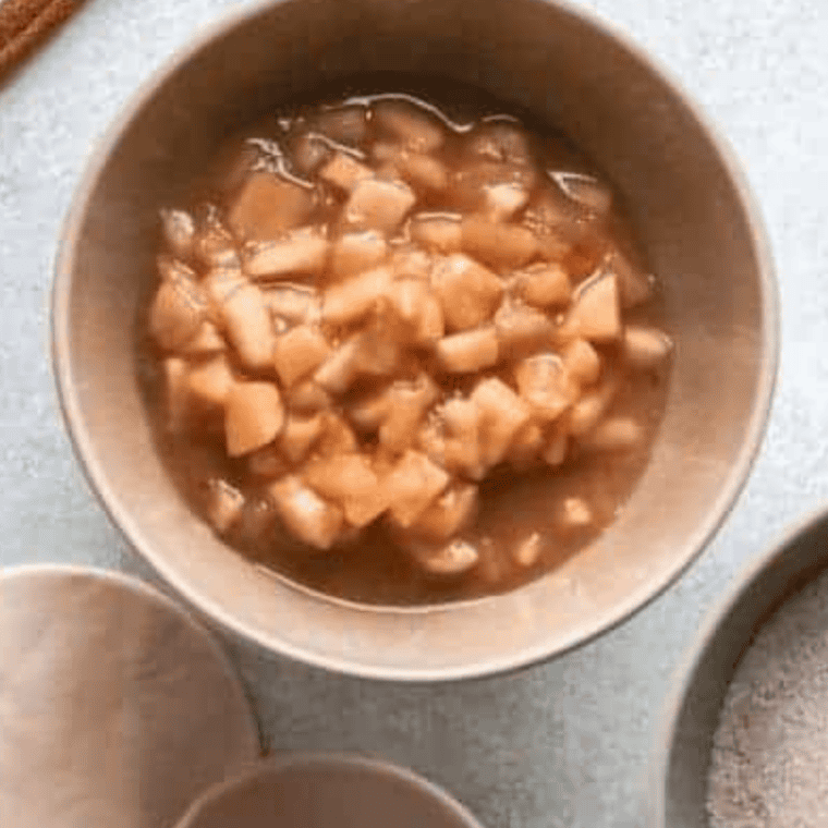 Diced apple pie filling, ground cinnamon, and granulated sugar combined in a small white mixing bowl for air fryer apple pie wontons