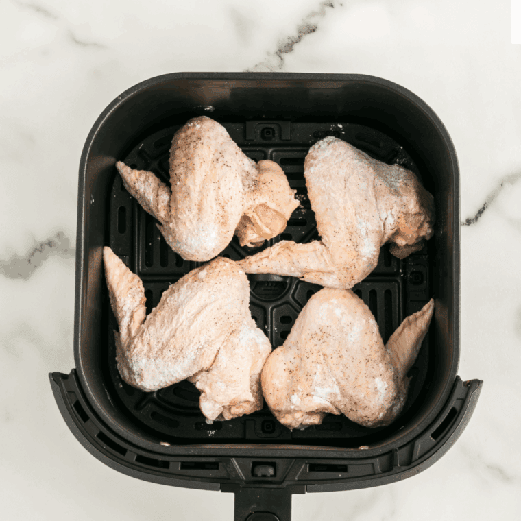 Chicken wings coated in chipotle-lime marinade, arranged in an air fryer basket, ready to cook at 380°F.