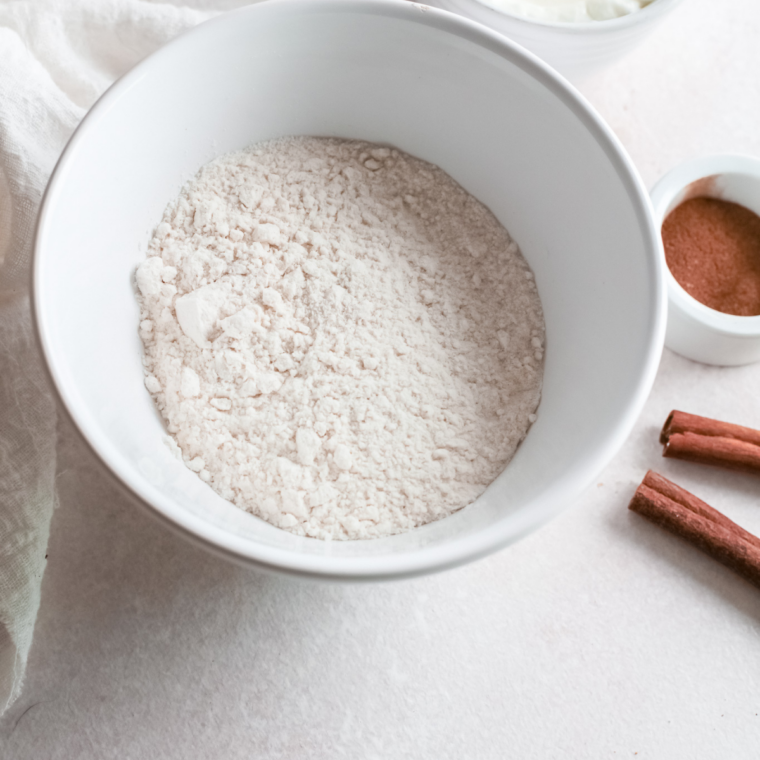 Flour, sugar, baking powder, and salt being whisked together in a large mixing bowl for funnel cake batter
