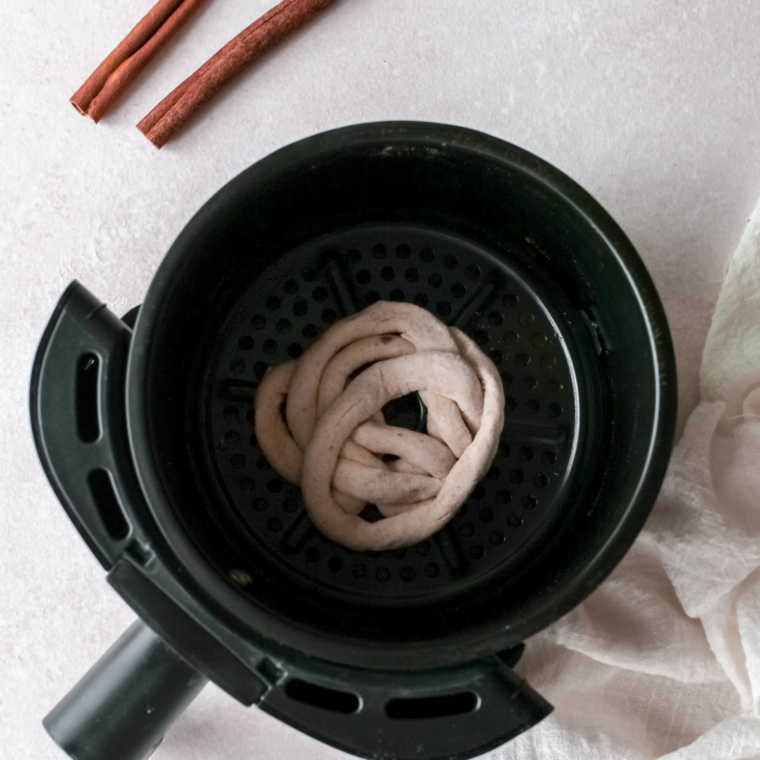 Air fryer basket lined with parchment paper and lightly sprayed with cooking spray before cooking funnel cakes