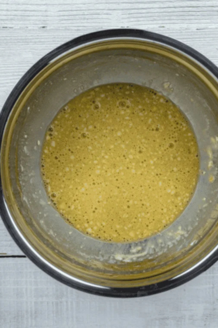Whisking eggs milk vanilla sugar and salt in bowl until smooth batter forms then adding flour and letting mixture rest for tender pancakes.