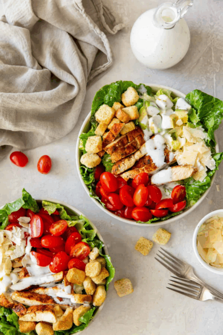 Close-up of tender grilled chicken sliced over fresh romaine lettuce in a Caesar salad.