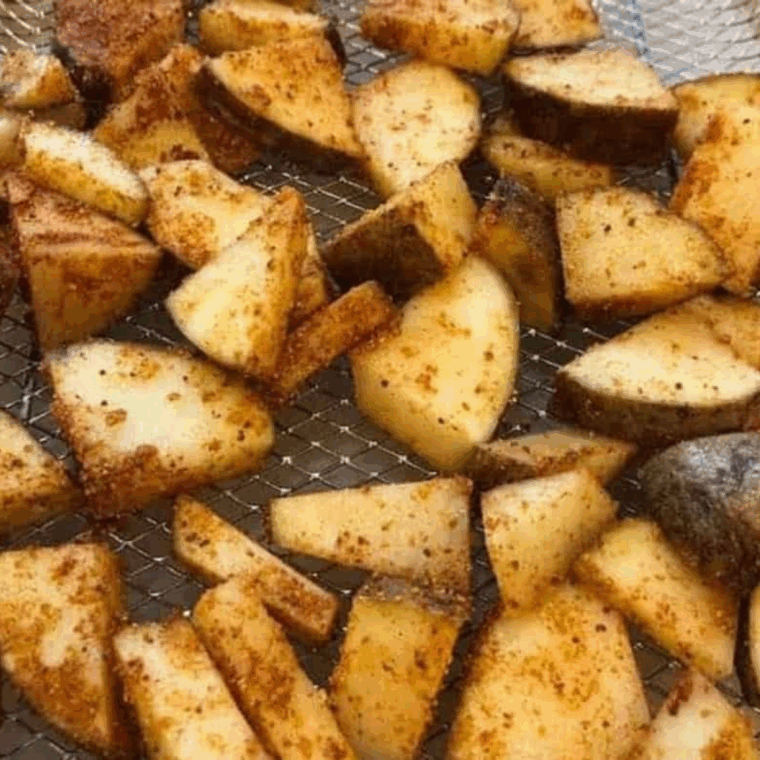 Golden air fryer red and Russet potato slices coated in maple BBQ seasoning, crispy outside, tender inside, served on a plate.