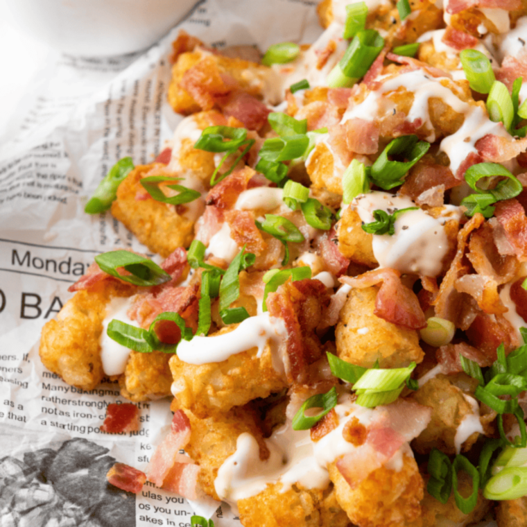 : Hot tater tots being tossed with copycat Potato Olé seasoning in a mixing bowl