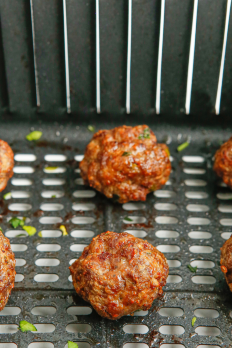 Meatballs arranged in single layer cooking in air fryer and flipped halfway for even browning and juicy texture.