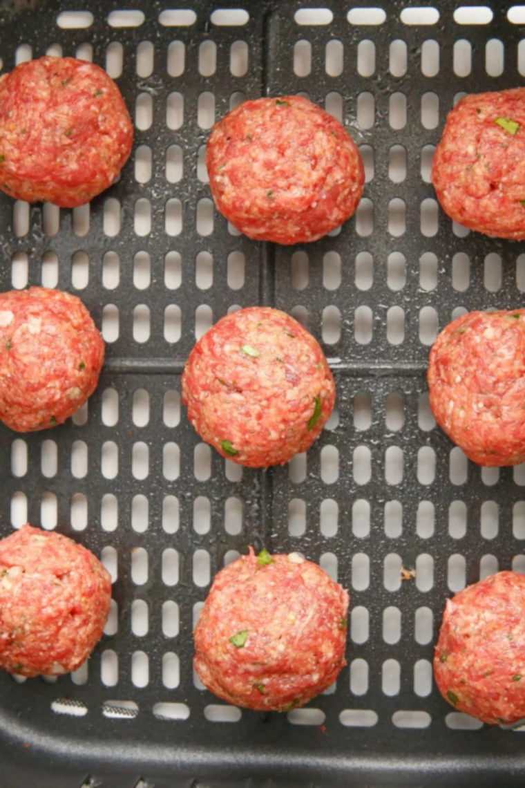 Air fryer preheated to high temperature with lightly greased basket ready for meatballs to develop a crisp exterior.