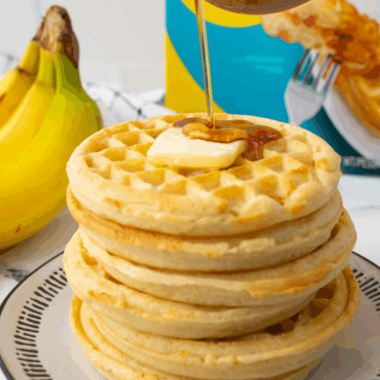 Frozen waffles cooking to golden crispiness in an air fryer basket.