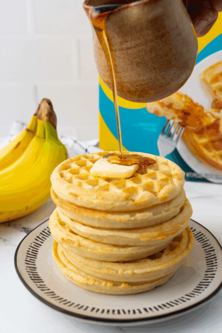Crispy golden frozen waffles cooking in an air fryer basket, ready to serve with syrup and fruit.