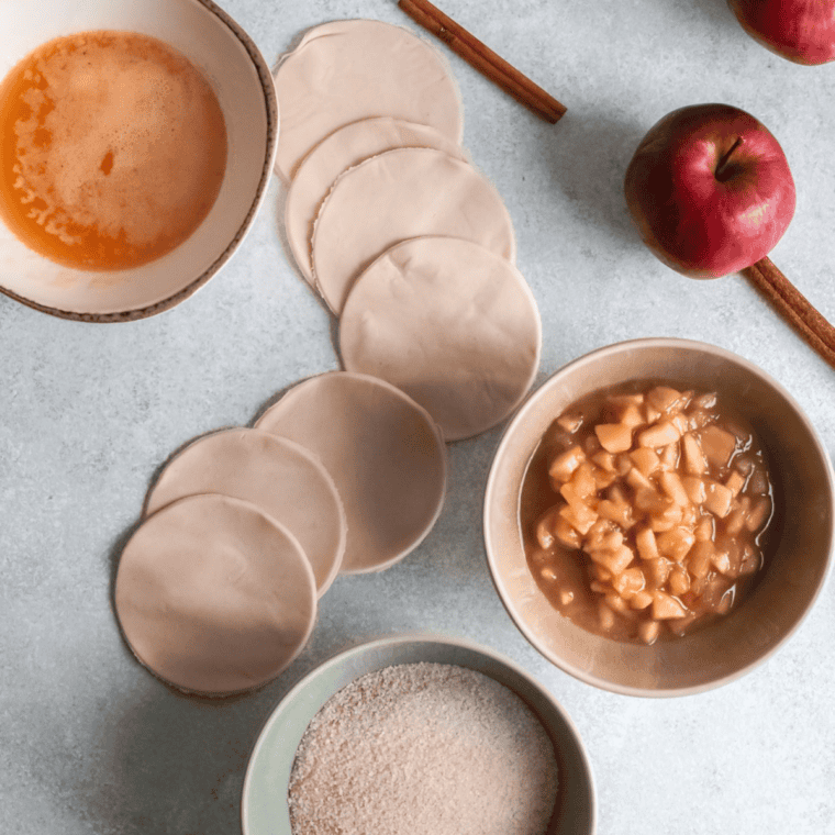 Ingredients for air fryer apple hand pies: pie crust, diced apples, sugar, flour, cinnamon, vanilla, and egg