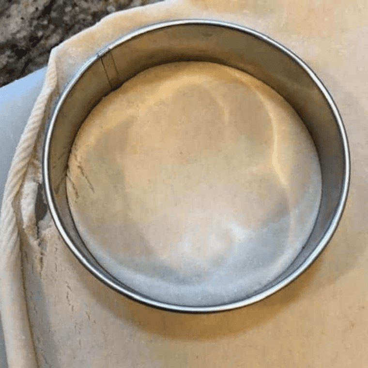 Cutting pie crust into rounds with a biscuit cutter to form hand pies