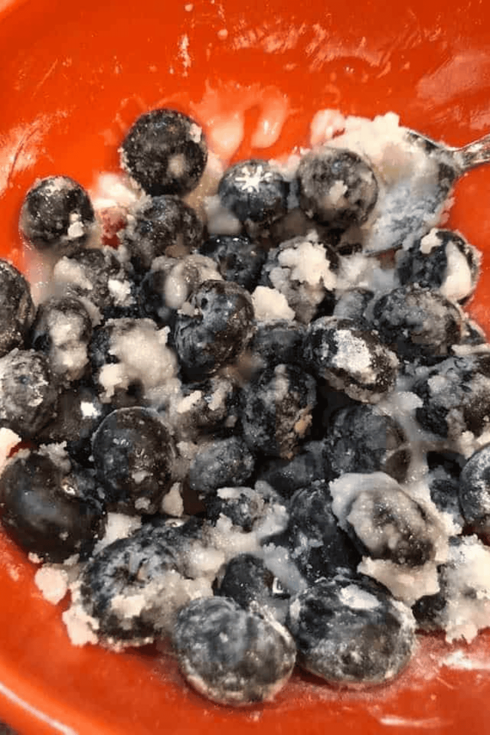 Mixing blueberries with sugar, lemon juice, and cornstarch for galette filling in bowl