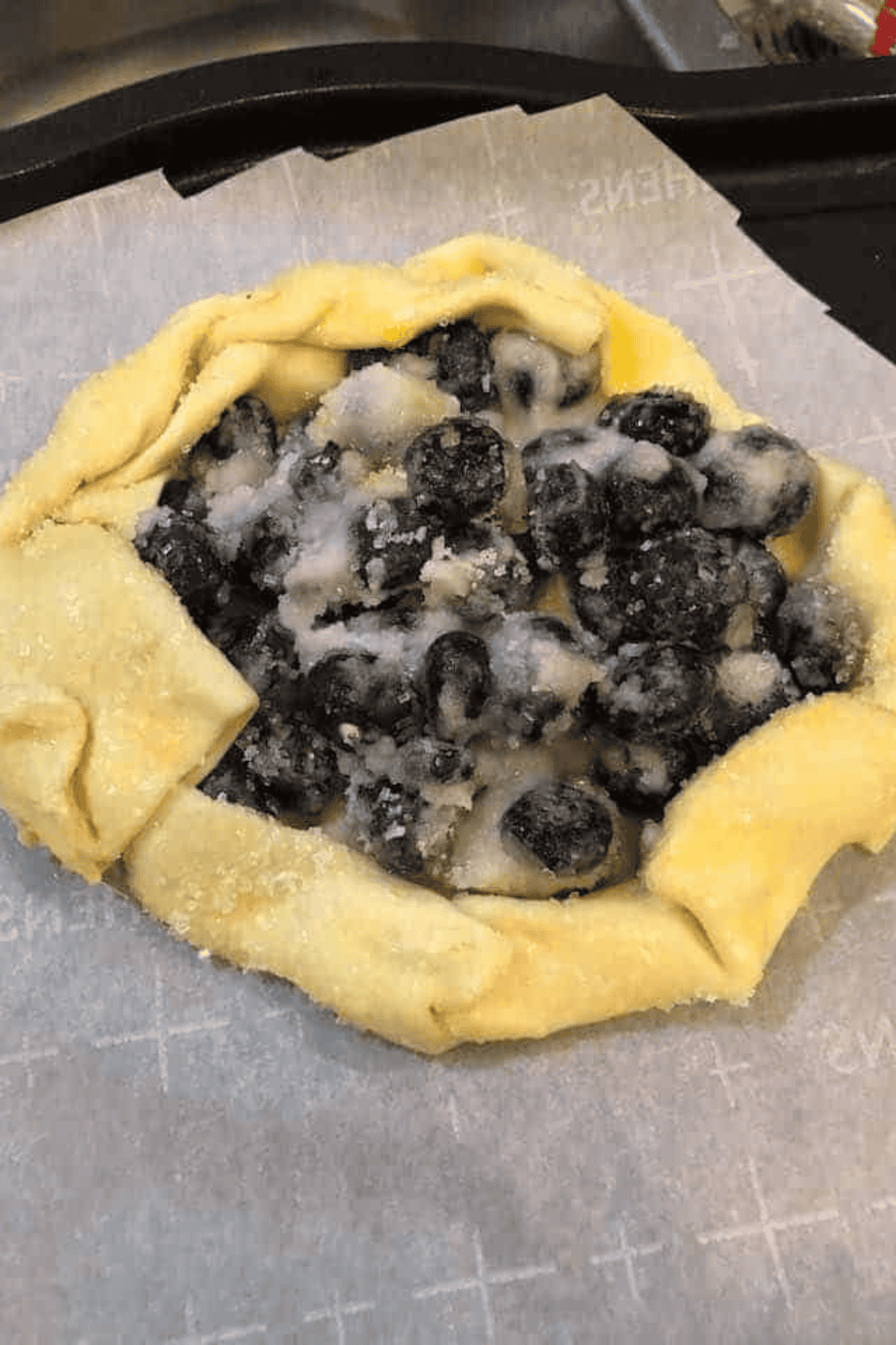 Blueberry filling placed in center of puff pastry before folding into galette