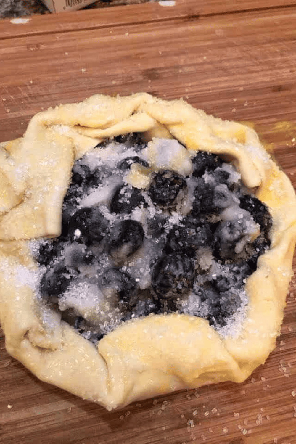 Folding puff pastry edges over blueberry filling and preparing egg wash
