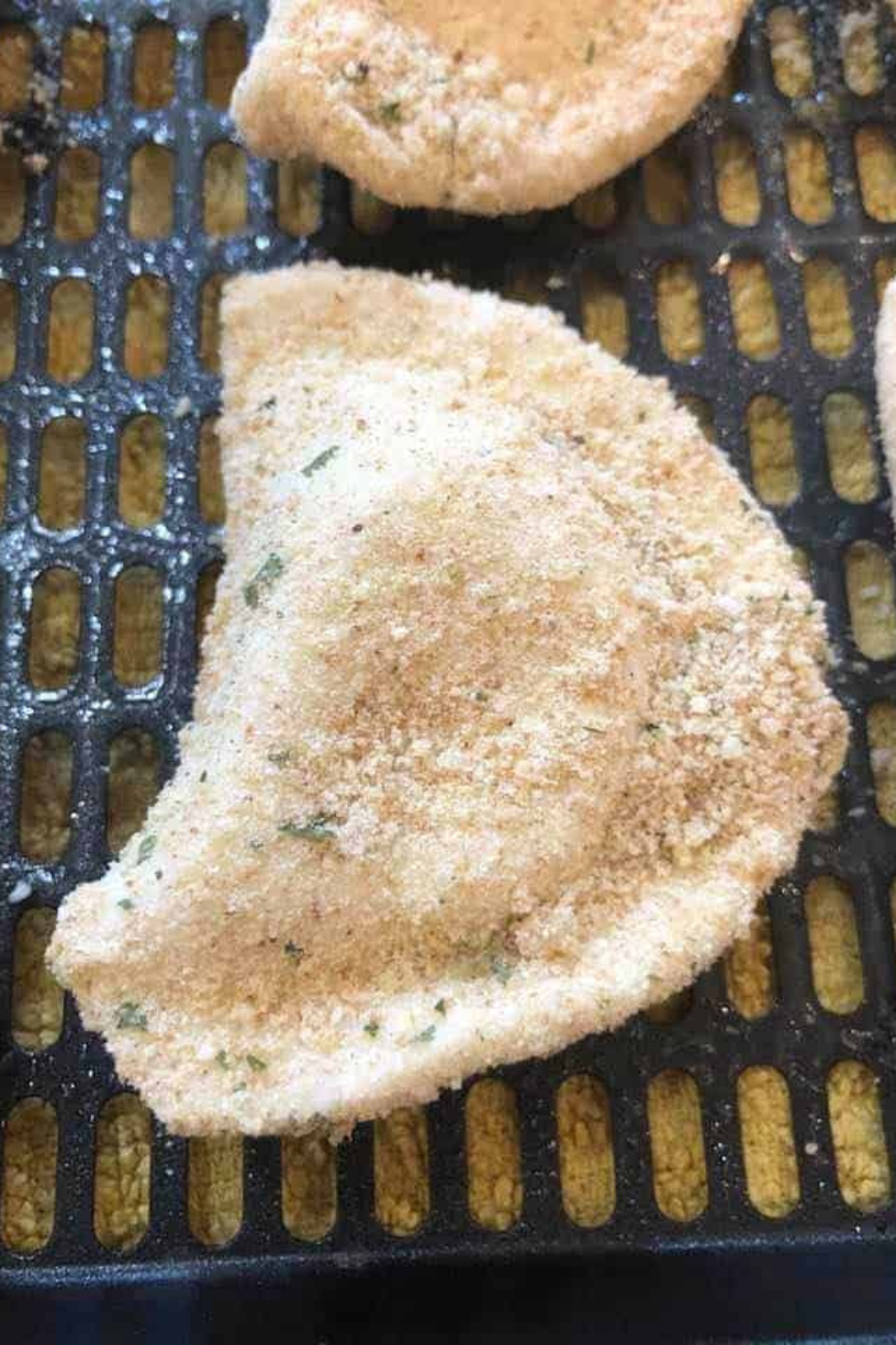 Breaded pierogies arranged in a lightly oiled air fryer basket, cooking to golden and crispy perfection.