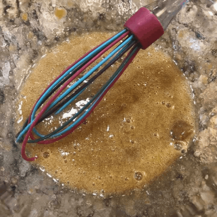 Mixing wet ingredients with dry flour and spices to make cinnamon sugar donut batter.