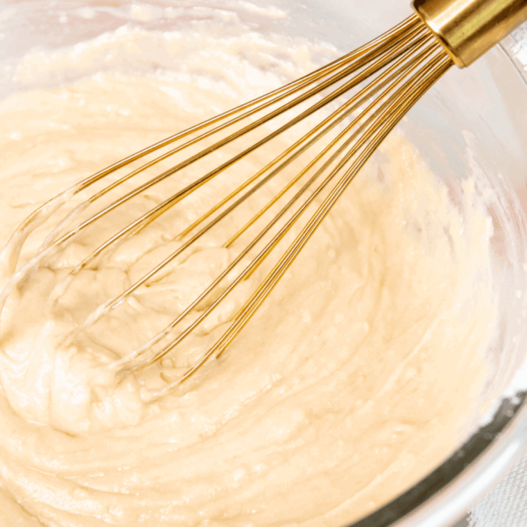 Mixing donut batter thoroughly and spraying the donut pan with olive oil.