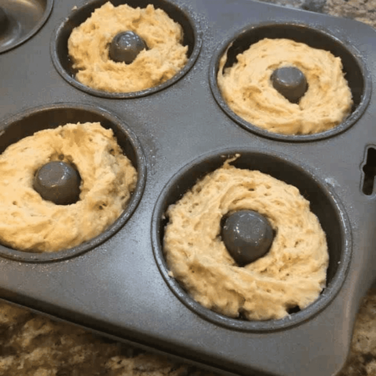 Donut pans filled with batter placed in air fryer, cooking until golden brown.