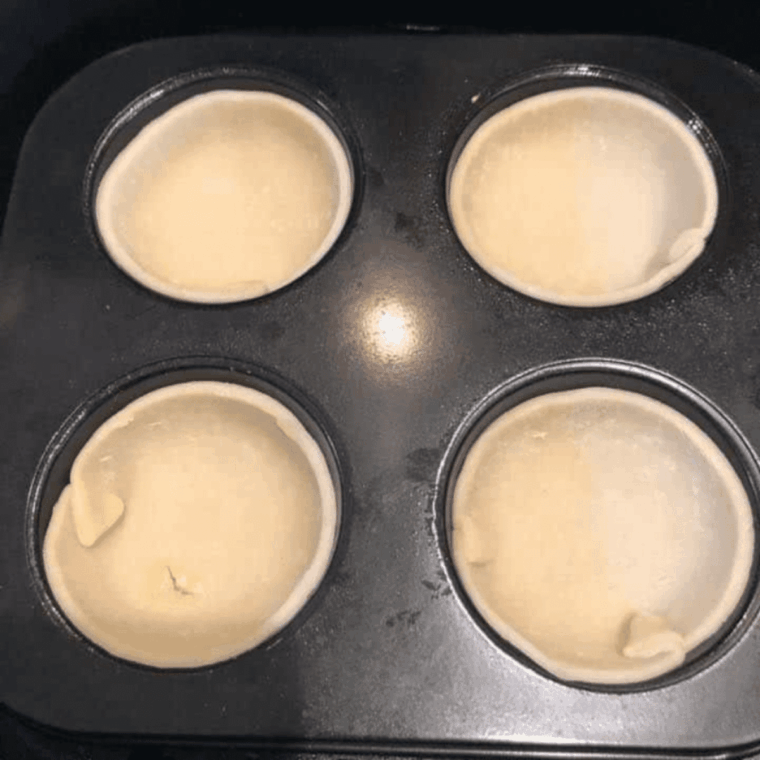 Dough-lined muffin tins placed in the air fryer, cooking until golden brown at 320&deg;F.