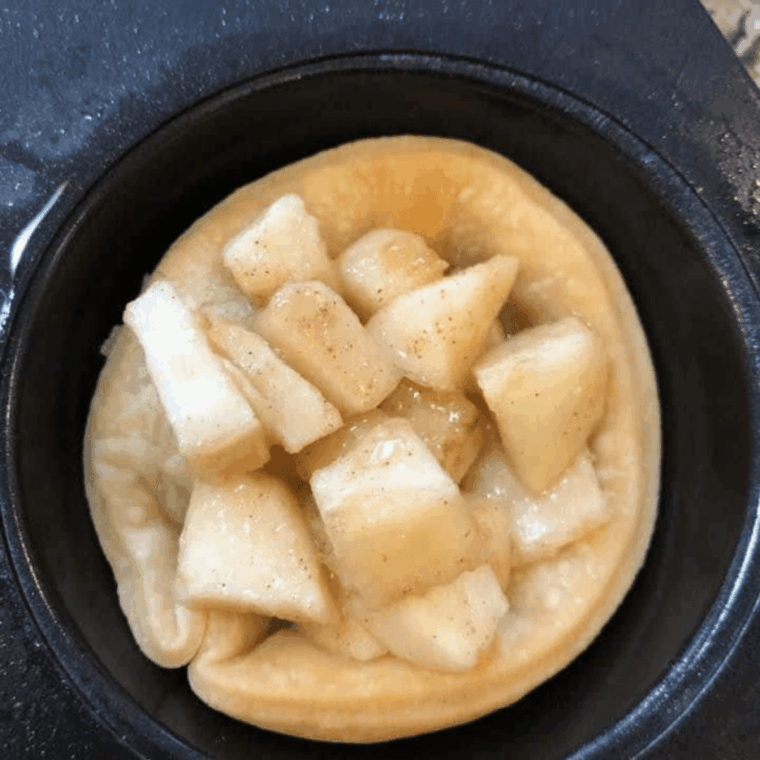 Mini muffin tin apple pies filled with pie filling, topped with lattice dough, brushed with butter, sprinkled with sugar, and air frying at 320&deg;F.