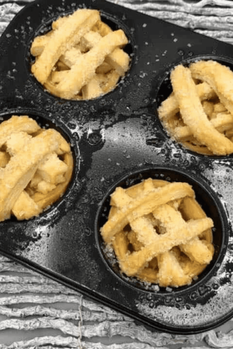Golden mini apple pies in an air fryer muffin tin with cinnamon-spiced apple filling