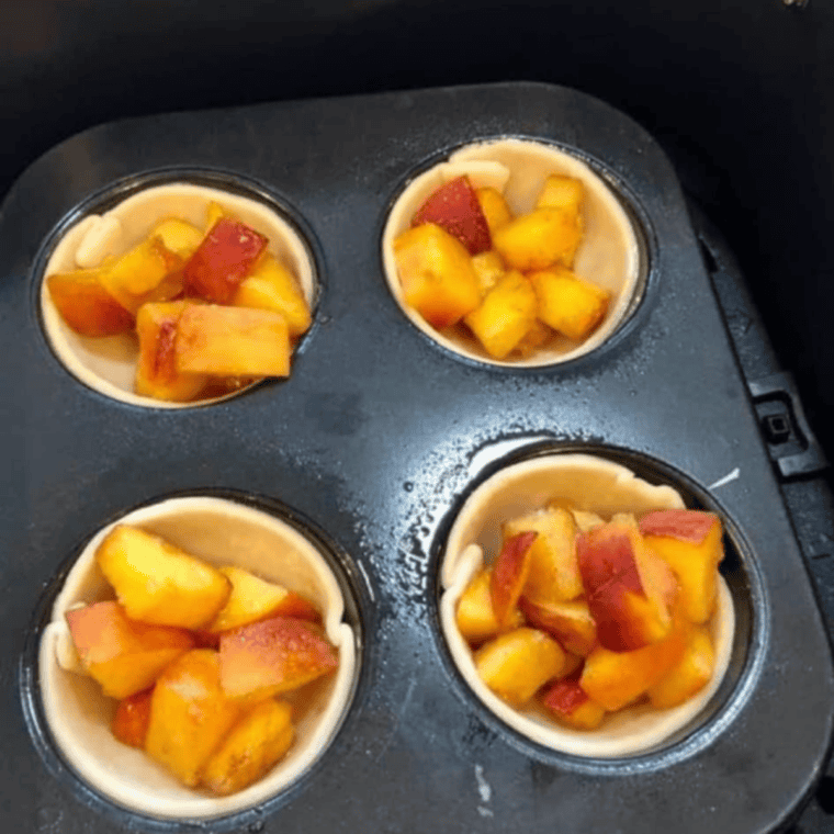 Easy Air Fryer Muffin Tin Peach Pies with golden crust and juicy peach filling, served in a muffin tin.