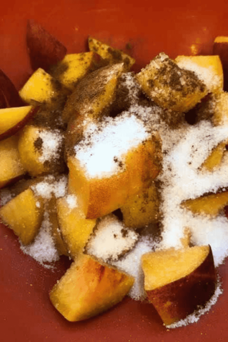 Mixing diced peaches with sugar and cinnamon in a small bowl for peach pie filling.