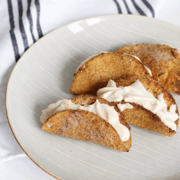 Crispy dessert tacos filled with apple pie filling and creamy cheesecake, served warm.