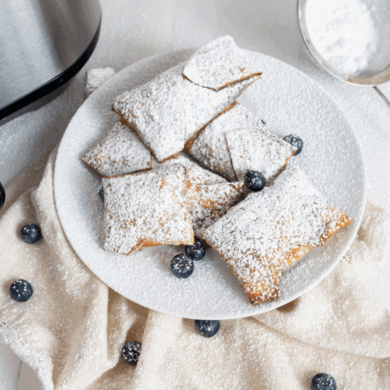 Golden air fryer blueberry cheesecake egg rolls with crispy edges and creamy filling, served on a plate.