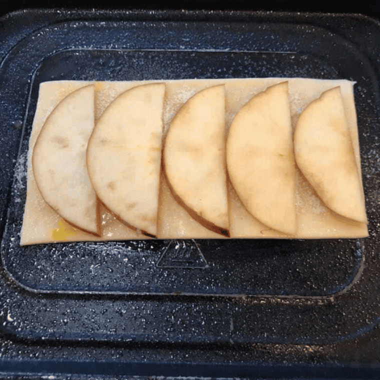 Thinly sliced apples arranged over cinnamon-sugar puff pastry before air frying