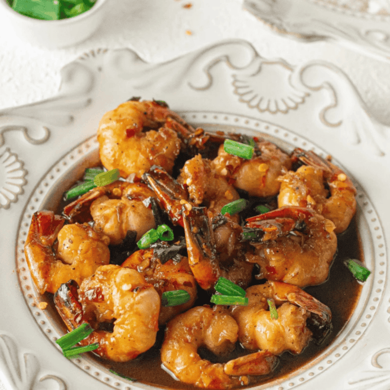 Air fryer honey garlic shrimp served in a bowl, topped with sauce and sliced scallions