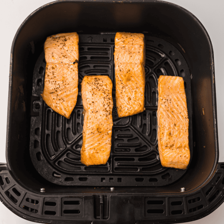 Cooked air fryer lemon Dijon salmon topped with sauce and garnished with fresh lemon wedges