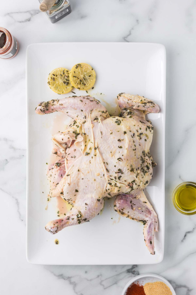 Brushing garlic herb seasoning onto spatchcock chicken