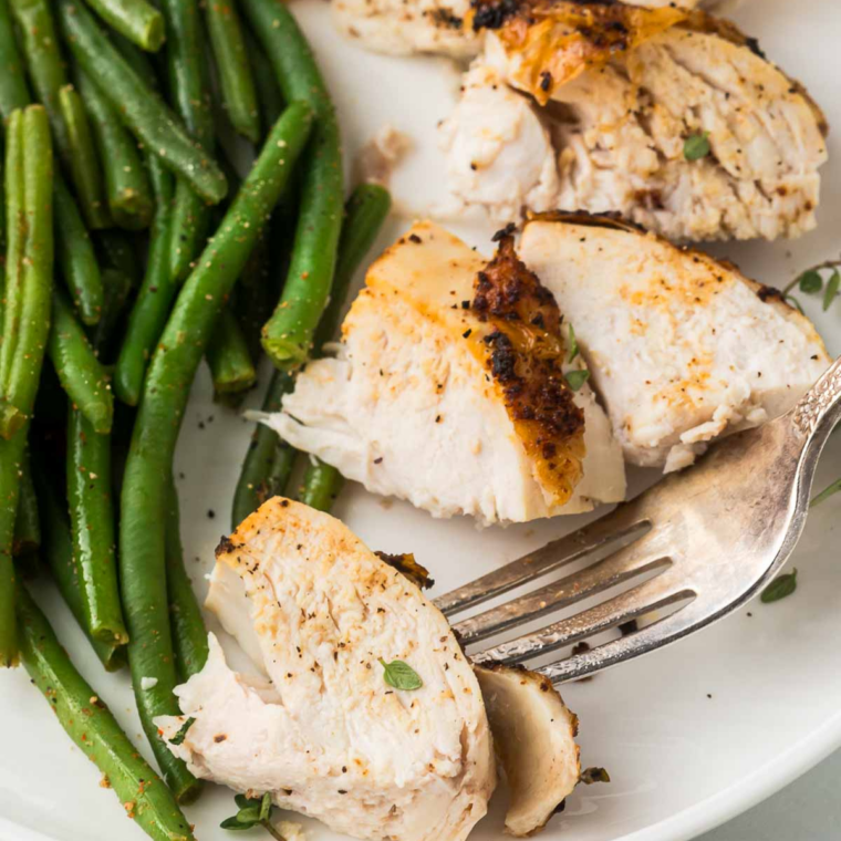Carved air fryer spatchcock chicken pieces served with green beans