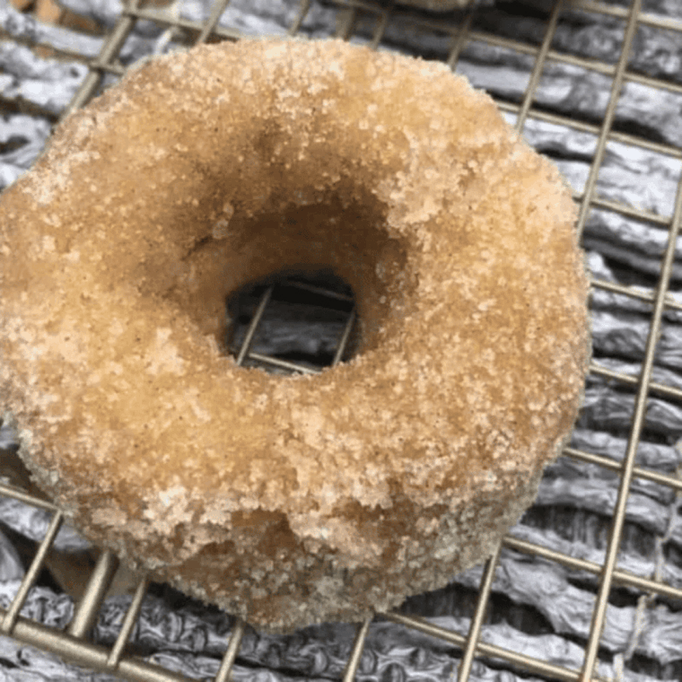 Golden air fryer apple cider donuts dusted with cinnamon sugar on a plate.