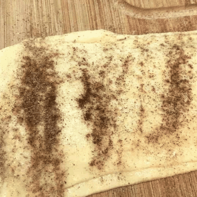 brushing melted butter on top of crescent dough and sprinkling with cinnamon-sugar mixture
