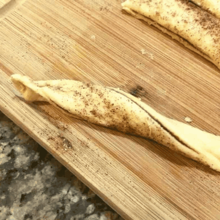 cutting apple pie pastry into strips with a pizza cutter, twisting them, and placing into a greased air fryer basket for cooking