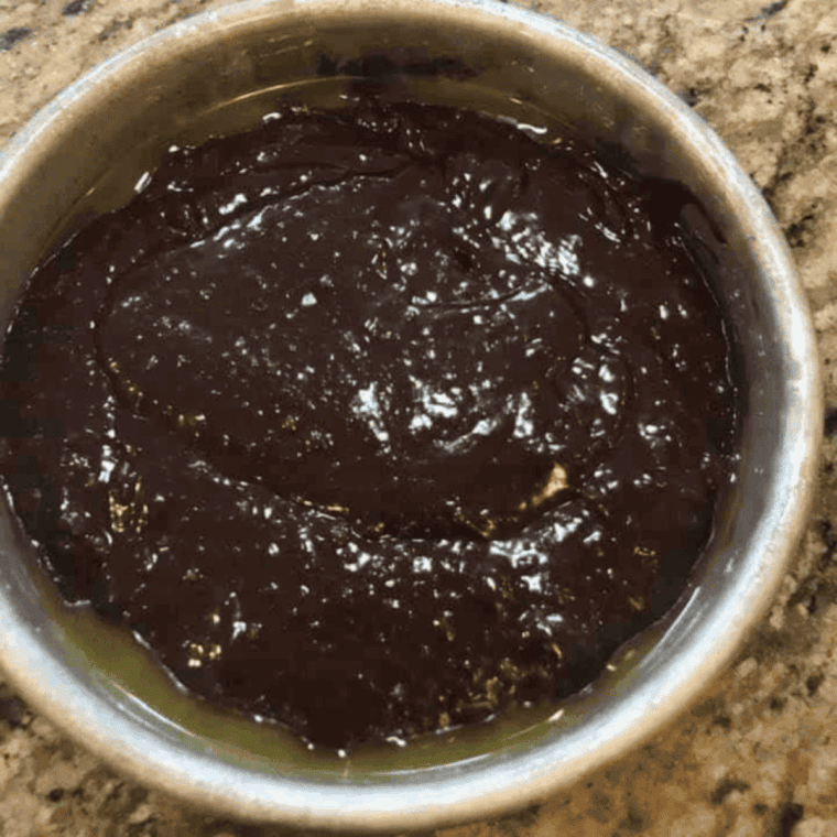 Pouring Nutella cake batter into greased pan for air fryer baking.